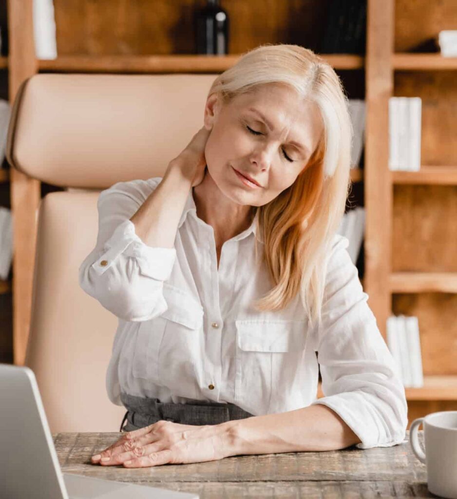 nie pozwól by bol kontrolował twoje życie - kobieta przy biurku dotyka dłonią szyi